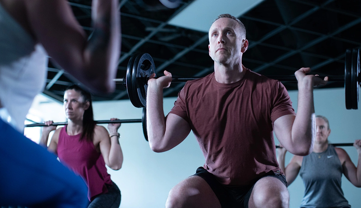 group fitness class using barbells to squat