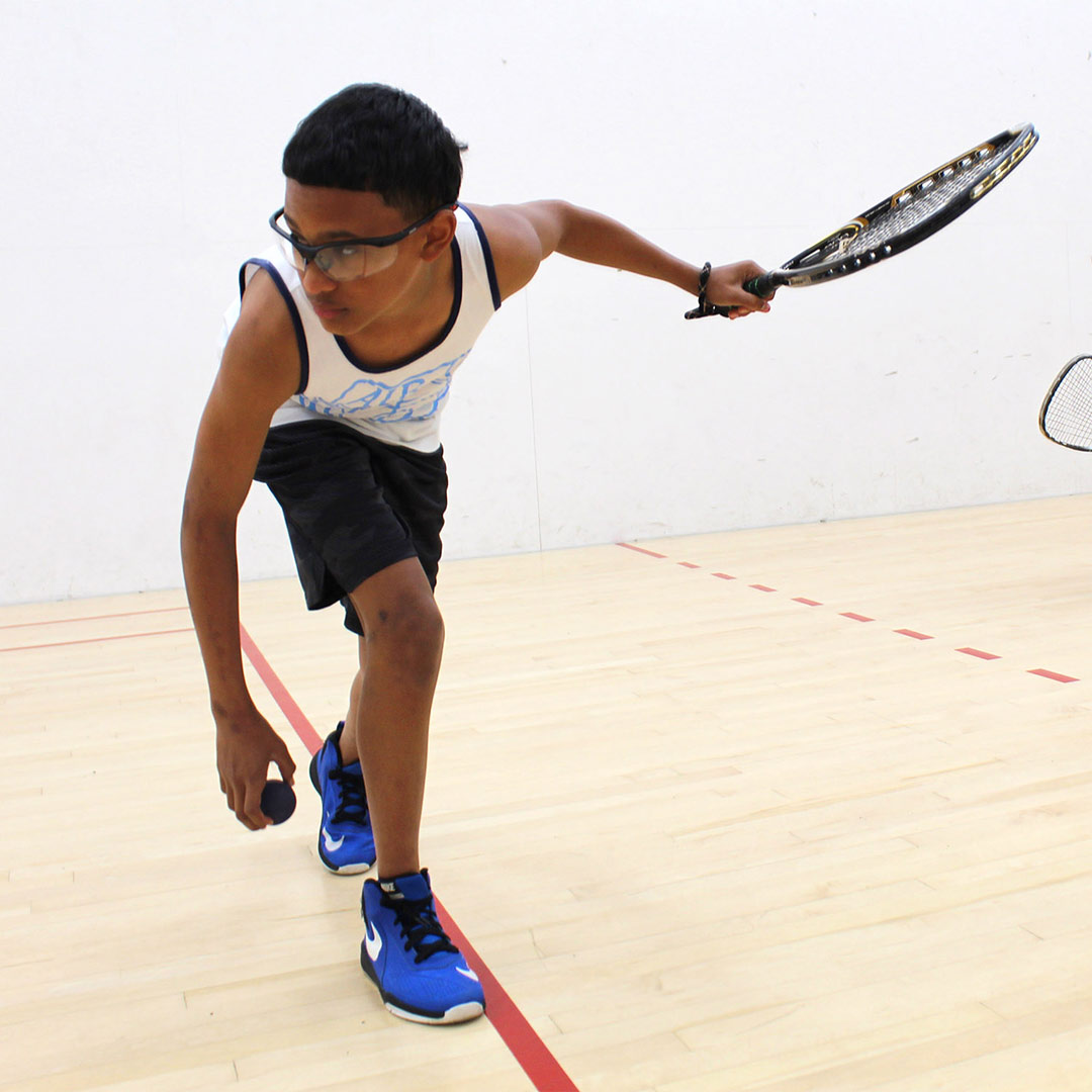 Younger Man playing racquetball indoors