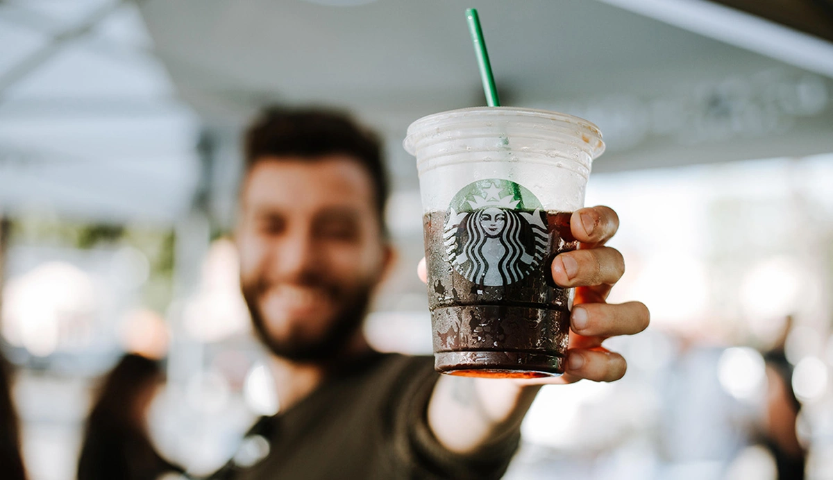 Man holding a Starbucks drink towards the camera.